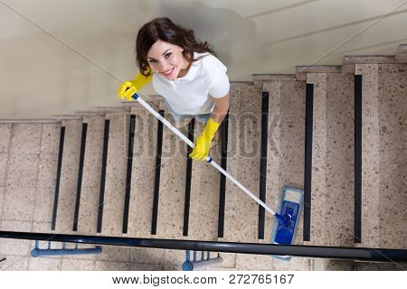 Young Female Janitor Cleaning Staircase With Mop