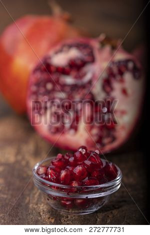 Seeds And Three Pomegranades On Dark Wood