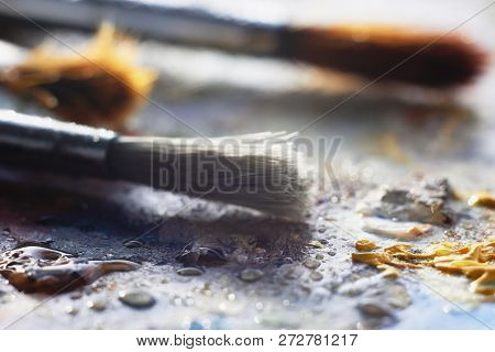 Three Brushes Are On A Wet Palette, Stained With Oil