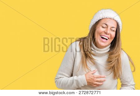 Beautiful middle age woman wearing winter sweater and hat over isolated background Smiling and laughing hard out loud because funny crazy joke. Happy expression.