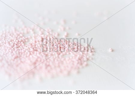 Pink Seed Beads Scattered On The Textile Background Close Up. Handmade Concept