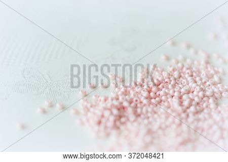 Pink Seed Beads Scattered On The Textile Background Close Up. Handmade Concept