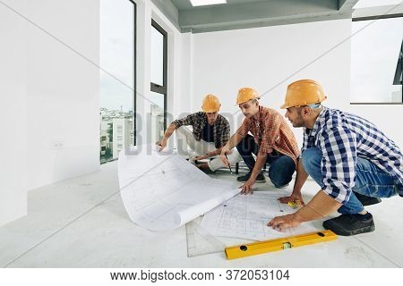 Middle Eastern Construction Engineers Sitting On Hunkers In Empty Room Of Unfinished Building Workin