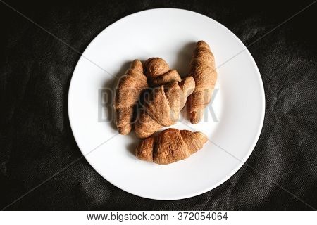 Croissants On A White Plate On A Black Textile Background. Fresh Bakery