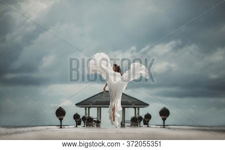 Bride By Sea. Jumping Woman In Wedding Dress. Sky And Sea Background. Wedding On Shore