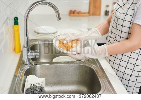 Kitchen Porter Cleaning White Plates In Sink In Professional Kitchen