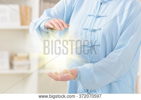 Beautiful woman doing qi gong tai chi exercise at home