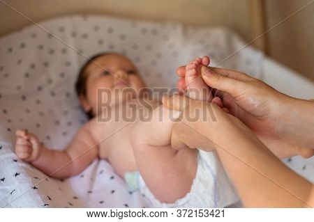 Hands Of Mother Or Masseuse Massaging Foot Of Infant Baby. Closeup Of Little Infant Receiving Feet R