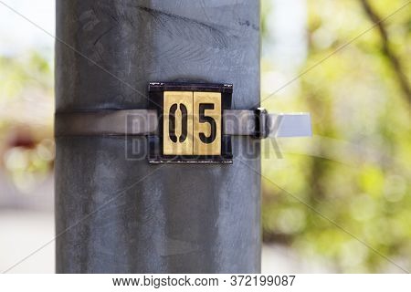 The Number Five On A Metal Tray With Green Bokeh In The Background