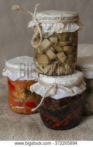 Jars Of Canned Food On Burlap. Several Glass Jars With Canned Mushrooms And Sun-dried Tomatoes.ingre