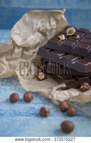A Piece Of Chocolate With Hazelnuts And Nuts On A Table