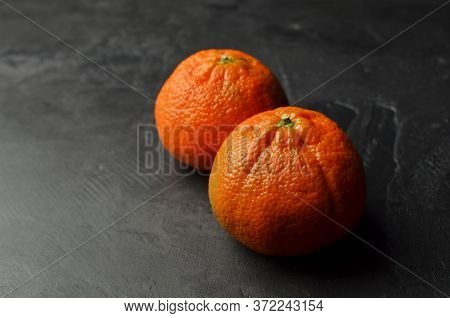 Two Big Whole Orange Mandarins On Black Background. Darkmood Food Pfotography. Copy Space.