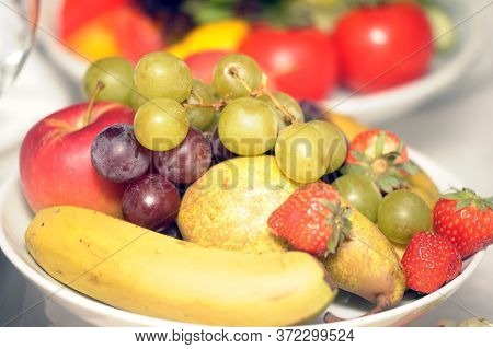 Fruit Bowl With Strawberries And Kiwi Grapes, Wine And Bananas On A Table With White Tablecloth