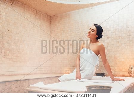 Beautiful Mixed Race Woman Sitting On A Marble Massage Table In A Hammam. Body Recovery At Hamam, Tu