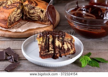 Marble Cake With Chocolate On Rustic Table. Chocolate Dripping From A Spoon