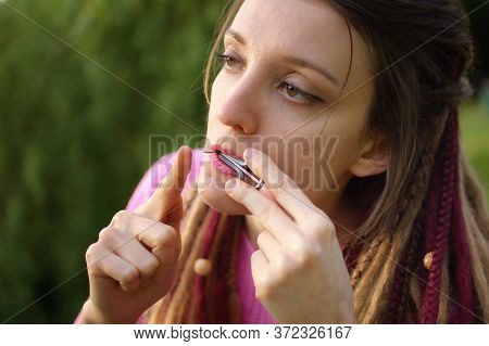 Close-up Outdoors Portrait Of Young Female Shaman In Pink Knitted Sweater With Long Dreadlocks Playi