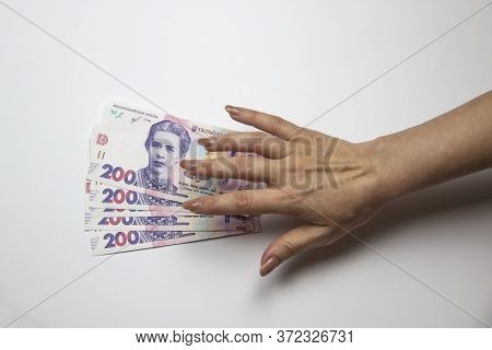 Female Hand Want To Touch A Thousand Hryvnia. Ukrainian Currency With Woman's Hand Against Backgroun