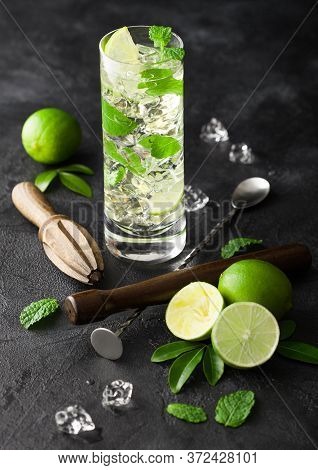 Highball Glass Of Mojito Cocktail With Ice Cubes,mint And Lime On Black Board With Spoon And Wooden 