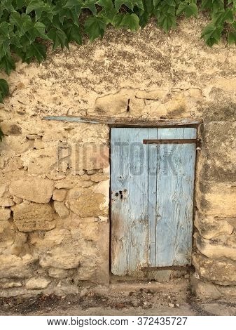 Old Wall In Stone With Blue Door In Wood In Ansouis,provence
