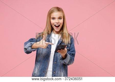 Excited Little Blonde Kid Girl 12-13 Years Old In Denim Jacket Posing Isolated On Pastel Pink Backgr