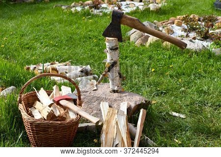 Woman Chopping A Log With An Ax In The Garden. Rural Life In The Summer. Chopping Firewood In The Fr