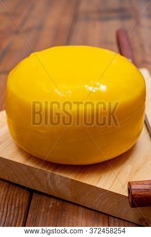 One Small Head Of Dutch Baby Gouda Cheese In Yellow Wax Close Up