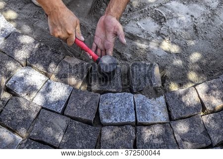 Worker Taps Granite Stones With A Rubber Hammer, Repairing The Sidewalk, Top View. The Process Of La