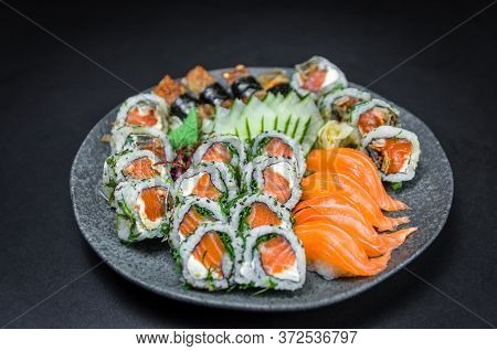 Sushi, Traditional Japanese Cuisine. Several Delicious Sushi On The Decorated Plate, Black Backgroun