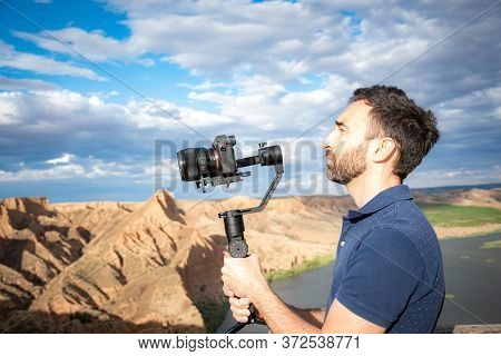 Young Filmmaker Filming Natural Landscape In Canyon With A Large River And Marshes