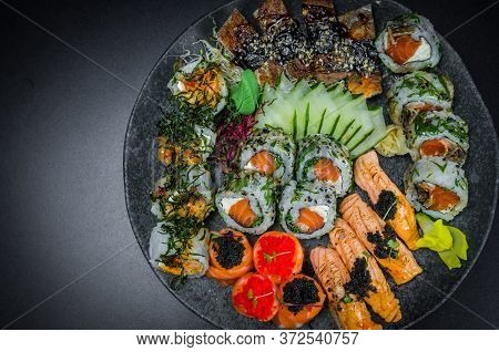 Sushi, Traditional Japanese Cuisine. Several Delicious Sushi On The Decorated Plate, Black Backgroun