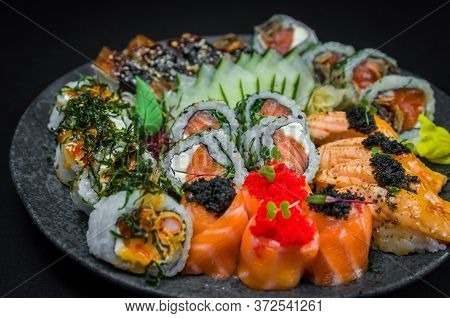 Sushi, Traditional Japanese Cuisine. Several Delicious Sushi On The Decorated Plate, Black Backgroun