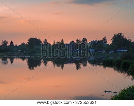 Old Fishing Village At Sunset In The Reflection Of The Water. Pudost Village. Russia.