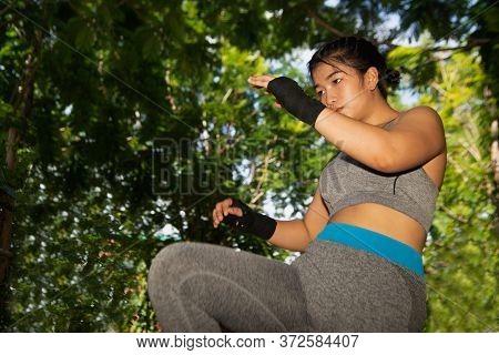 Beautiful Young Asian Woman 20-30 Year Old Posing With Black Boxing Gloves Punching In The Park.