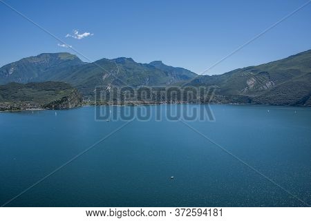 Beautiful View Of Lake Garda From The Ponale Road, With The Blue Sky, Sailing Boats, And The Green O