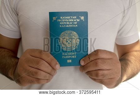 Kazakhstan Passport In Male Hands. Man In White T-shirt Is Holding Kz International Passport, Light 