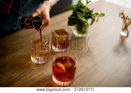 Close-up Woman Pours Drink From Jigger Into Glass
