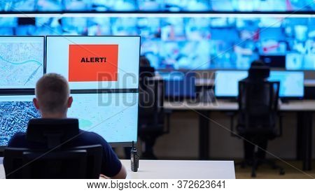 Male security operator working in a data system control room offices Technical Operator Working at  workstation with multiple displays, security guard working on multiple monitors  Male computer opera