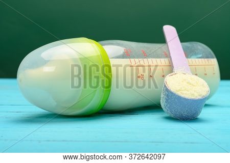 Glass Baby Bottle With Powdered Milk And A Scoop Nearby