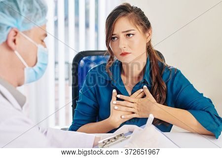 Frustrated Young Woman Compaining About Chest Pain When Talking To Her Physician