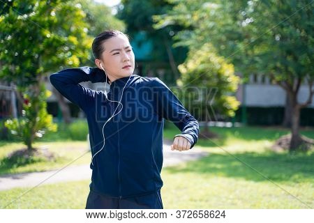 Portrait Of Asian Woman Wearing Earphones Listening To Music Was Sick With Fever At Park. Woman Exer