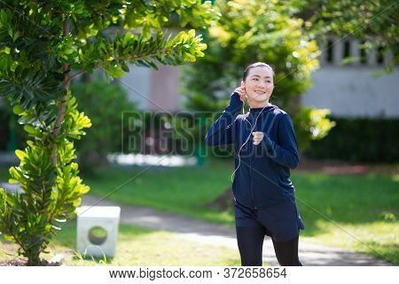 Portrait Of Asian Woman Wearing Earphones Listening To Music Was Sick With Fever At Park. Woman Exer