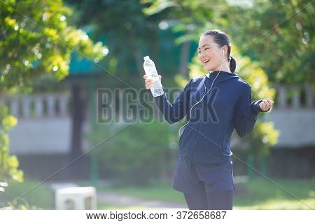 Portrait Of Asian Woman Wearing Earphones Listening To Music Was Sick With Fever At Park. Woman Exer