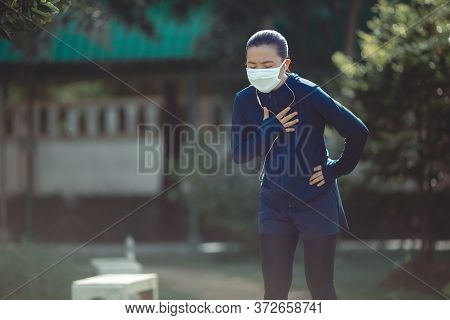 Portrait Of Asian Woman Wearing Earphones Listening To Music Was Sick With Fever At Park. Woman Exer