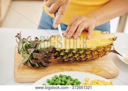 Close-up Image Of Woman Cutting Fresh Ripe Pineaaple With Sharp Ceramic Knife