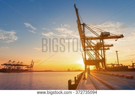 Crane At International Container Sea Port At The Sunrise  Stand By For Loading Cago Container To Shi