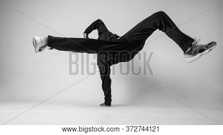 A Man Hip Hop Dancer Or Bboy Freezes In One Pose On A White Background. Bboy Doing Stylish Stunts.
