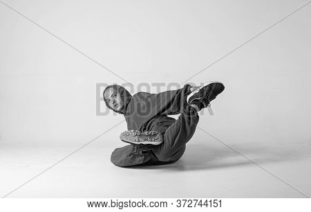 A Man Hip Hop Dancer Or Bboy Freezes In One Pose On A White Background. Bboy Doing Stylish Stunts.
