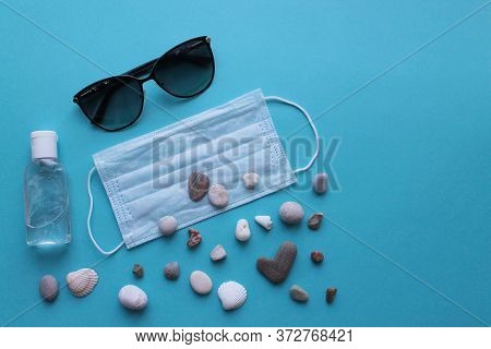 Sunglasses, Pebbles, Medical Mask And Antiseptic On A Wooden Background. The Tourist Crisis In The S