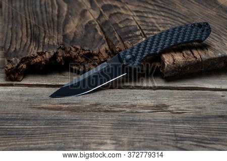 A Sharp Knife With A Black Carbon Handle And A Black Blade.