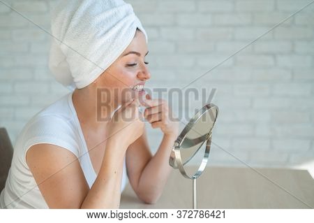 A Woman Looks In A Table Mirror And Crushes Acne On Her Chin. An Unhappy Girl With Problem Skin Does